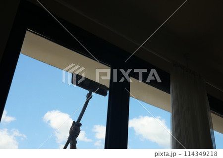 Rubber squeegee cleans a soaped window. 114349218