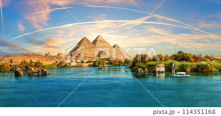 Lonely Saleboat in the Nile river and ancient rocks in the Aswan desert by the pyramids, Egypt 114351168