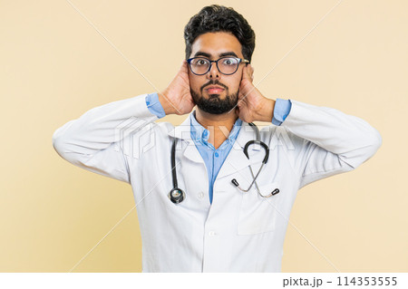 Annoyed irritated doctor man covering ears gesturing no avoiding advice ignoring noise loud voices 114353555