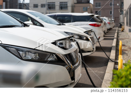 Electric EV car parked in the parking lot while plugged in for charging Electric EV car parked in the parking lot while plugged in for charging 114356153