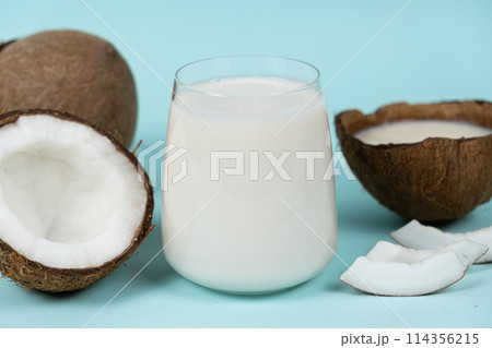 Healthy vegan coconut milk in a glass and coconut shell on a blue background. 114356215