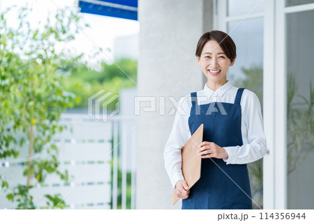 カフェの店内に案内する女性 114356944