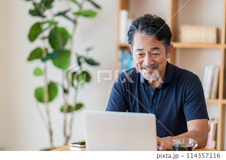 リビングで株式投資をするシニア男性。 114357116