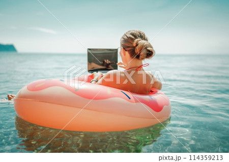 Woman laptop sea. Freelancer woman in sunglases floating on an inflatable big pink donut with a laptop in the sea. People summer vacation rest lifestyle concept Woman laptop sea. Freelancer woman in sunglases floating on an inflatable big pink donut with a laptop in the sea. People summer vacation rest lifestyle concept 114359213