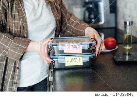 Healthy diet plan for weight loss, daily ready meal menu. Plus size young Woman holding lunch boxes just cooked in advance, ready to be served. Containers with eco healthy food. Pre-cooking concept. 114359849