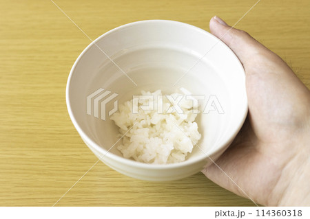茶碗に入れた少しのご飯を持つ男性の手。貧困のイメージ 茶碗に入れた少しのご飯を持つ男性の手。貧困のイメージ 114360318