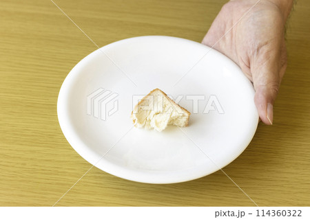 皿にのせた少しのパンを持つ男性の手。貧困のイメージ 皿にのせた少しのパンを持つ男性の手。貧困のイメージ 114360322