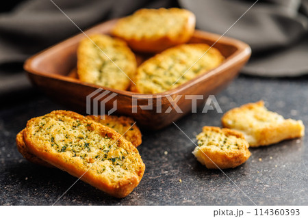 Garlic crisp bread Slices Topped With Herbs on black table. Garlic crisp bread Slices Topped With Herbs on black table. 114360393