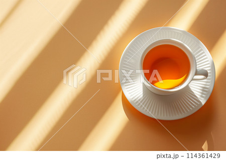 Cup of tea on a beige surface with sunlight casting striped shadows, copy space Cup of tea on a beige surface with sunlight casting striped shadows, copy space 114361429