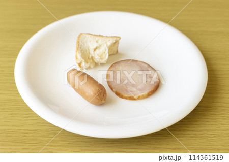 皿にのせた少しのパンとチキンとソーセージ。貧困のイメージ 114361519