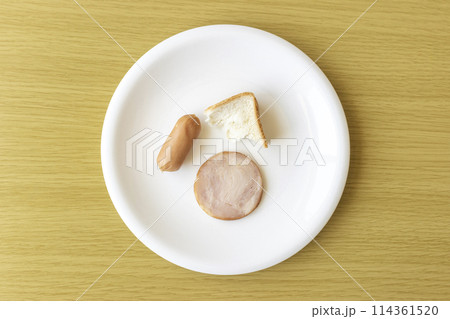 皿にのせた少しのパンとチキンとソーセージ。貧困のイメージ 皿にのせた少しのパンとチキンとソーセージ。貧困のイメージ 114361520