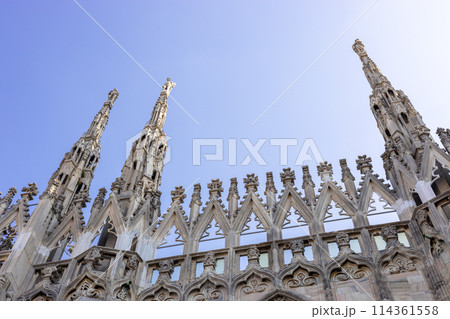 Roof of Milan Cathedral Duomo di Milano with Gothic spires and white marble statues. Top tourist attraction on piazza in Milan, Lombardia, Italy. Gothic architectural fragment Roof of Milan Cathedral Duomo di Milano with Gothic spires and white marble statues. Top tourist attraction on piazza in Milan, Lombardia, Italy. Gothic architectural fragment 114361558