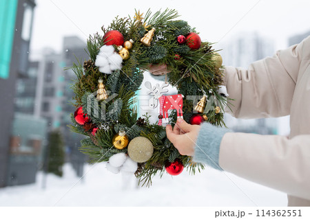 Person Holding Christmas Wreath in Snow 114362551