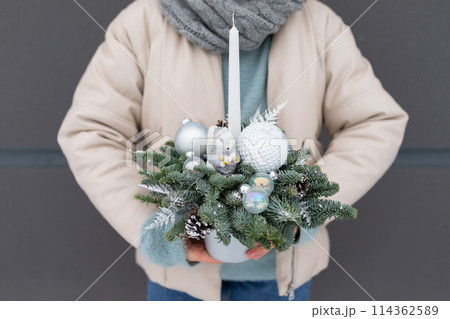 Person Holding Christmas Arrangement, holiday decorations and colors. 114362589