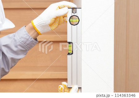 水平器（水準器、レベル）を使って壁の垂直を調べる作業員 114363346