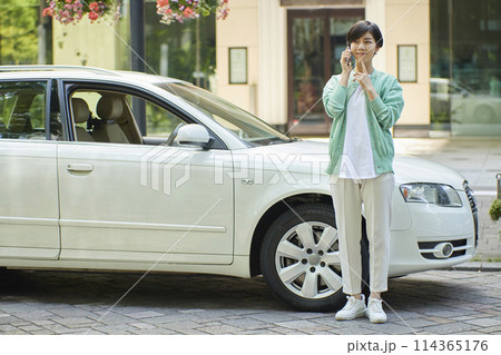 車の前でスマホを使用する若い女性 車の前でスマホを使用する若い女性 114365176