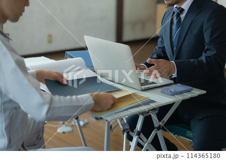 打ち合わせするスーツと作業着の男性 114365180