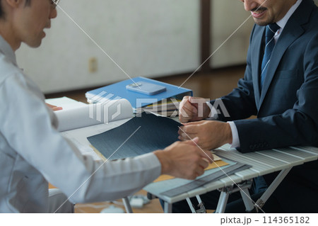 打ち合わせするスーツと作業着の男性 114365182