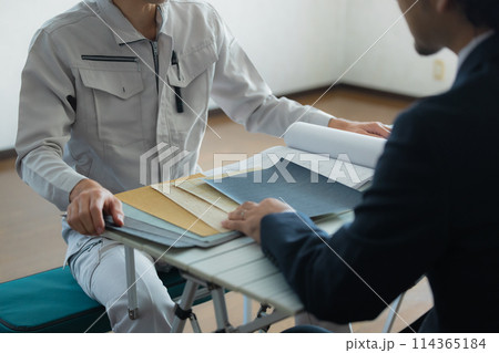 打ち合わせするスーツと作業着の男性 114365184