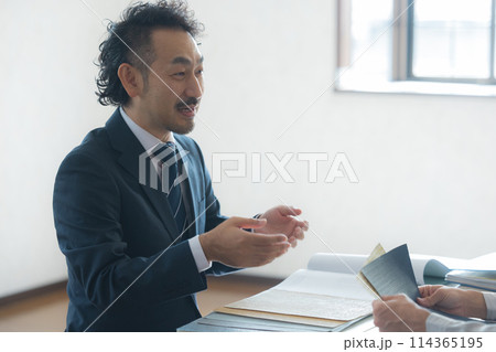 打ち合わせするスーツと作業着の男性 打ち合わせするスーツと作業着の男性 114365195