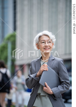 オフィス街でpcを持つシニア女性 オフィス街でpcを持つシニア女性 114365321