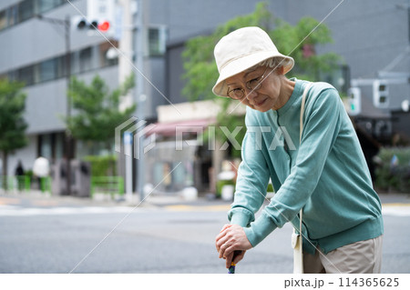 杖をついて考え事をする高齢者女性 114365625
