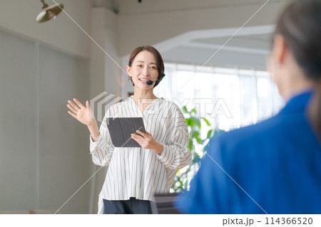 マイクを持って説明をするビジネスパーソン マイクを持って説明をするビジネスパーソン 114366520