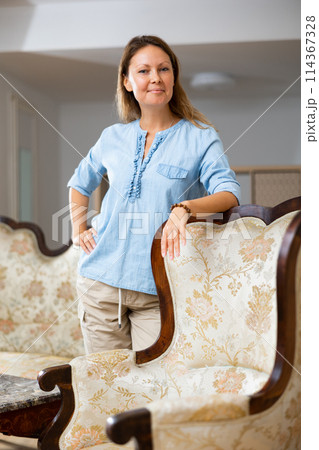 Positive woman standing near sofa at home Positive woman standing near sofa at home 114367328
