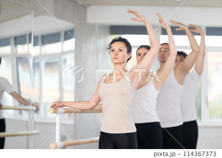 Group of dancers stand in third position at barre Group of dancers stand in third position at barre 114367373