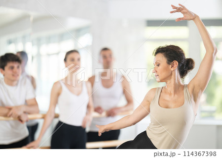 Female ballet instructor demonstrating dance movements to group Female ballet instructor demonstrating dance movements to group 114367398