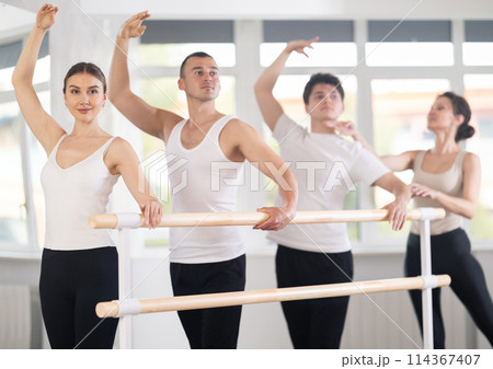 Female trainer corrects dancers at barre 114367407