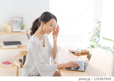部屋でパソコンを見る30代女性 部屋でパソコンを見る30代女性 114367426
