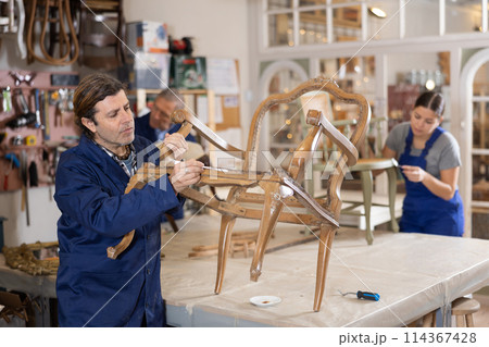 man restorer spackling antique chair surface getting piece of furniture ready for further coloring man restorer spackling antique chair surface getting piece of furniture ready for further coloring 114367428