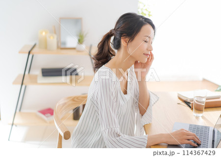 部屋でパソコンを見る30代女性 部屋でパソコンを見る30代女性 114367429