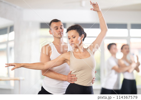 Portrait of young man practicing in classical ballet with young beautiful woman in black and white clothing in ballet hall 114367579