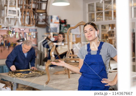 Smiling young female carpenter showing around local furniture workshop Smiling young female carpenter showing around local furniture workshop 114367667
