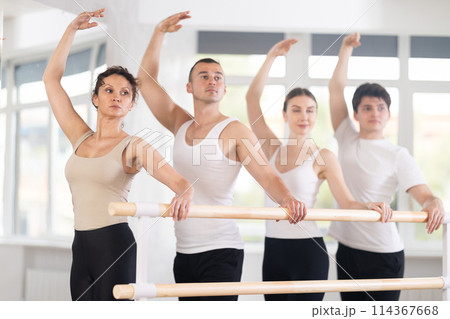 Woman performing third ballet position in group barre workout 114367668
