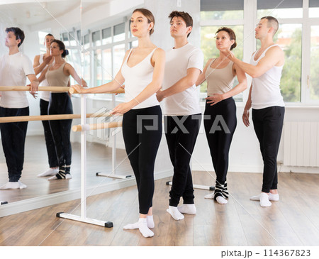 Young man trainer corrects dancers at barre 114367823