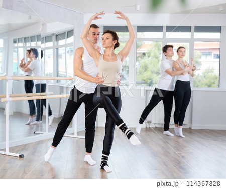 Ballet dancer providing support of female partner in challenging movements Ballet dancer providing support of female partner in challenging movements 114367828