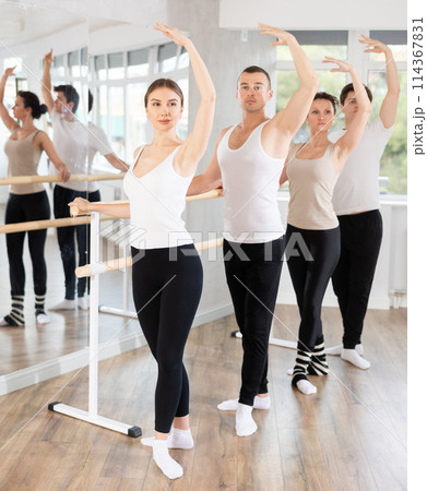 Group of dancers stand in fourth position at barre Group of dancers stand in fourth position at barre 114367831