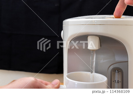 電気ポットからカップにお湯を注ぐ 114368109
