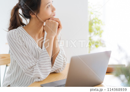 頬杖をして横を向いている女性 114368939