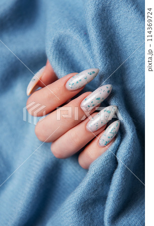 Female hands with blue nail design on blue textile background. Female hands with blue nail design on blue textile background. 114369724