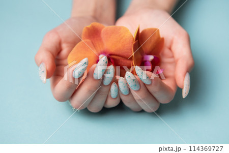 Female hands with blue nail design on blue pastel background 114369727