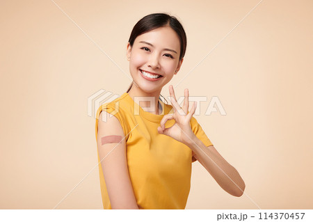 Healthy asian woman getting vaccinated immunity giving ok hand sign on beige background, concept of recommended inoculation, vaccination, 114370457