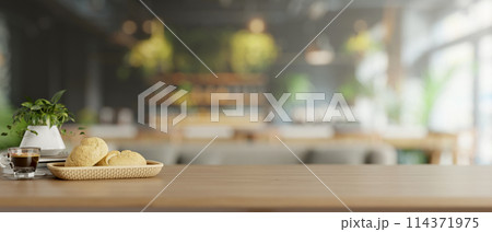 A wooden tabletop features a bread basket and a coffee cup in a modern restaurant or coffee shop. 114371975