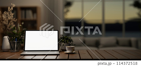 A white screen laptop computer mockup on a wooden table in a modern dark living room. A white screen laptop computer mockup on a wooden table in a modern dark living room. 114372518