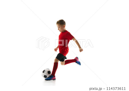 Little athlete boy, training dribbling ball and passing in motion against white studio background. Young soccer player. Little athlete boy, training dribbling ball and passing in motion against white studio background. Young soccer player. 114373611