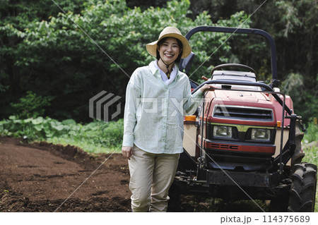 畑の前に立つトラクターと女性 畑の前に立つトラクターと女性 114375689