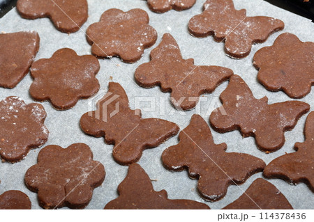 On the baking sheet laid blanks for baking gingerbread. They are on food paper. Cooking gingerbread. 114378436